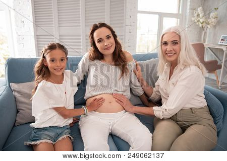 Beautiful Women. Three Beautiful Appealing Women Sitting On Dark Blue Comfortable Sofa In Living Roo