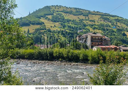 High Houses With Balconies And Small Traditional Huts On The Shore Of A Swift River At The Foot Of A