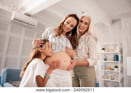 Hugging Woman. Beaming Happy Grandmother And Daughter Feeling Amazing While Hugging Pregnant Woman