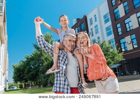 Family Traditions. Delighted Nice Family Smiling While Having A Walk Together In The Neighborhood