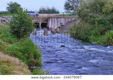 Car Bridge Over A Small, Stormy River With Foggy Water On Rapids