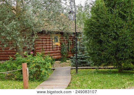 A Wooden House With A Path Surrounded By Trees In Summer.