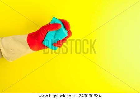 Hand Holding A Sponge For Dishes On Pastel Yellow Background