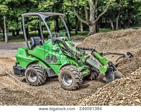 Green skid loader with a load of gravel
