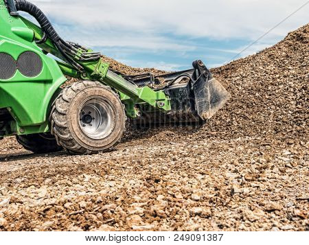 Green skid loader loading gravel
