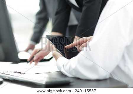 Image of human hand pointing at touchscreen in working environme