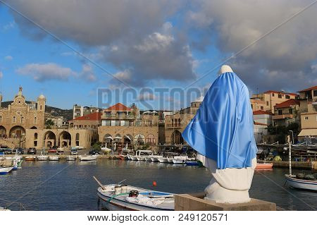 A White Statue Of The Virgin With A Blue Cloth Protecting The Port Of Batroun, Lebanon.