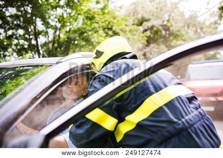 An Unrecognizable Firefighter Getting An Unconscious Man Out Of The Car After An Accident.