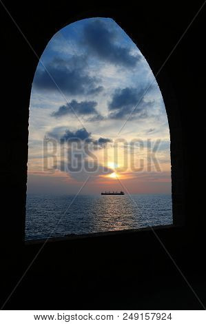 A Ship In The Mediterranean Sea Viewed Through An Arch During Sunset In Batroun, Lebanon.