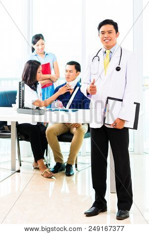 Asian doctor examining patient with toby collar and fracture in his office or clinic