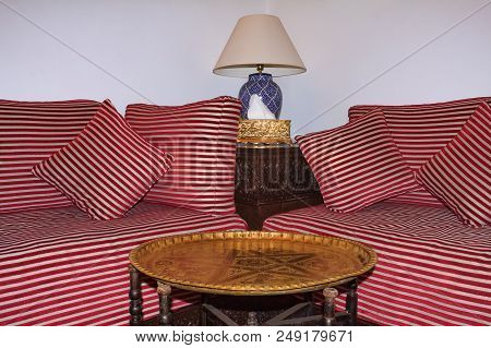Moroccan Couches And Cushions With An Ornate Metal Coffee Table Ina Sitting Area Of A Riad Courtyard