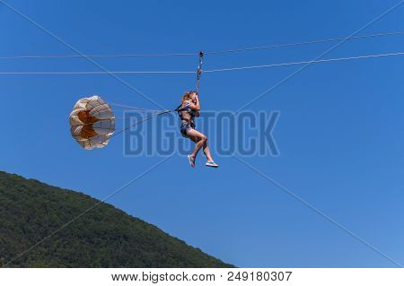 A Woman Riding Along The Cable Clutching Her Hands With A Stick With Rollers Tied For Back Insurance