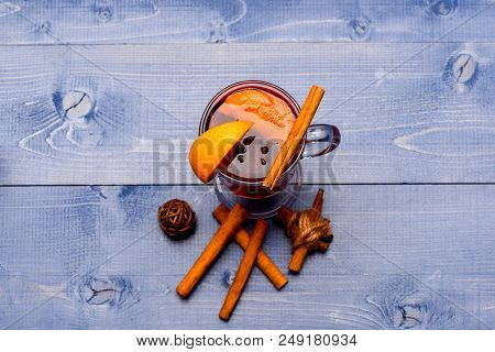 Mulled Wine Near Pile Of Cinnamon. Glass With Mulled Wine Or Hot Cider Near Cinnamon Sticks On Blue 