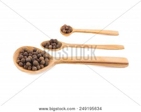Three Wooden Spoons Of Different Size And Shape Are Filled With Peppercorns, Situated On The White B