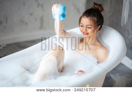 Happy Model Putting Foam On Her Legs In The Modern Bathroom