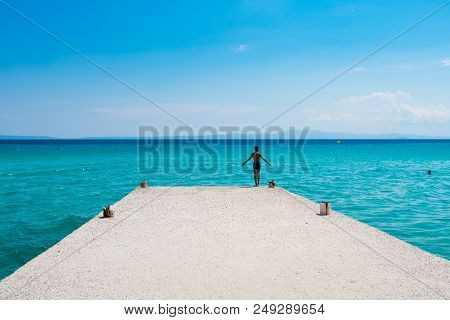 Chaniotis, Greece - June 23, 2018:young Boy Preparing To Jump Into The Sea On A Sunny Day