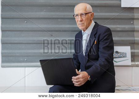 An Old Businessman Dressed In A Black Official Suit Is Working In The Ofiice With The Help Of His No