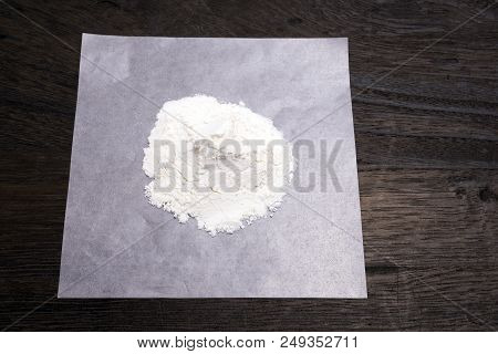 White Medicine Powder On Paraffin Paper On A Dark Brown Table