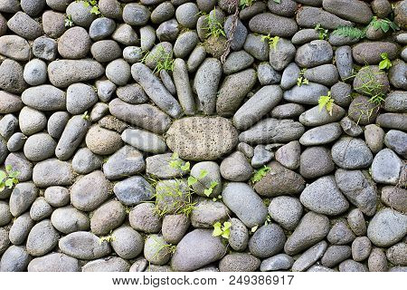 Stone Flower On A Stone Wall With Green Grass