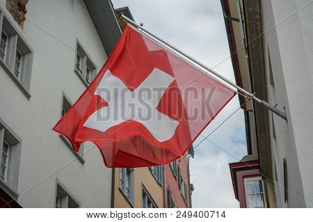 Swiss Flag Hanging From Building Facade In Old Town