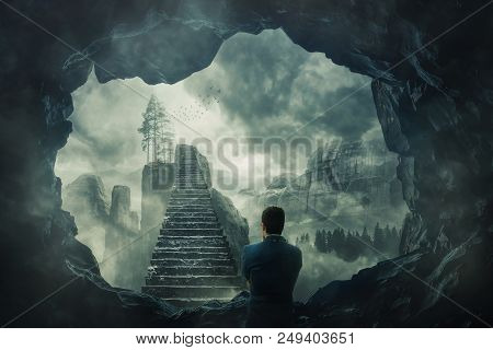 Surreal View As A Man Escape From A Dark Cave Stand In Front Of A Mystic Stairway Crossing The Misty