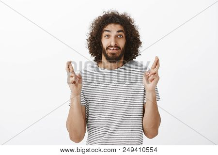 Shot Of Worried Handsome Bearded Eastern Male Model With Afro Hairstyle In Striped T-shirt, Raising 