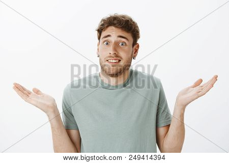 Close-up Shot Of Questioned Awkward Handsome Male In Earrings, Shrugging And Spreading Palms Clueles