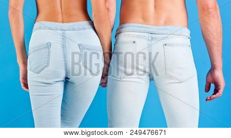 Ass Of Young Couple. Man And Woman Holding Hands. Young Couple Unrecognizable In Jeans On Blue Backg