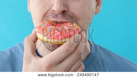 Man Is Eating A Pink Donut Closeup On A Blue Background
