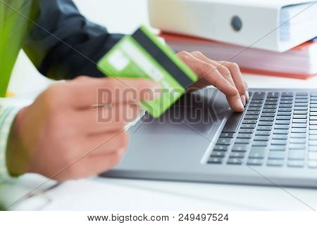 Young Businessman Holding A Credit Card And Typing. On-line Shopping On The Internet Using A Laptop