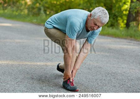 Active Healthy Mature Sportsman Stands Sideways, Feels Pain In Leg After Long Jogging, Wears Sneaker