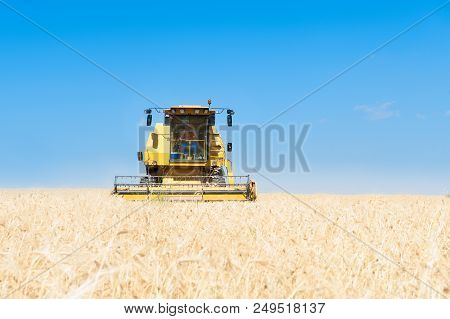 Harvester In The Foreground On Rustic Background Working In The Field