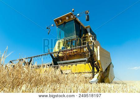 Harvester In The Foreground On Rustic Background Working In The Field