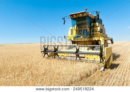 Harvester In The Foreground On Rustic Background Working In The Field