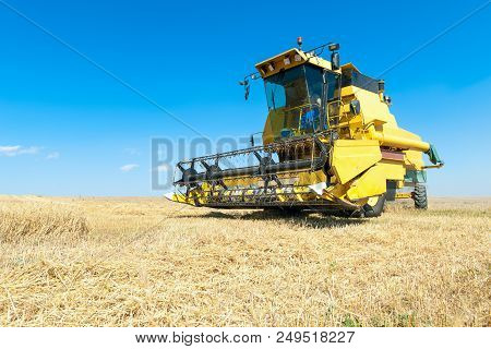 Harvester In The Foreground On Rustic Background Working In The Field