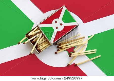 Burundi Flag  Is Shown On An Open Matchbox, From Which Several Matches Fall And Lies On A Large Flag