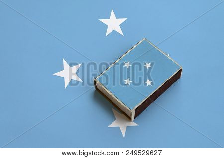 Micronesia Flag  Is Pictured On A Matchbox That Lies On A Large Flag.