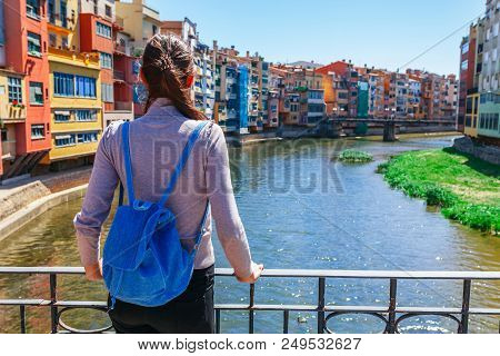 Tourist Woman See On Colorful Red And Yellow Houses And Bridge River Onyar In Girona, Catalonia, Spa