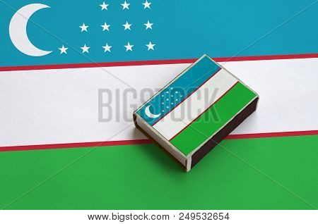 Uzbekistan Flag  Is Pictured On A Matchbox That Lies On A Large Flag.