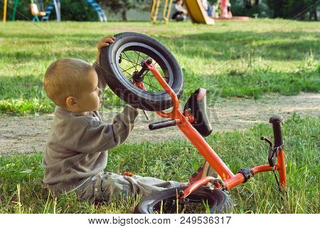 A Little Boy Dreams Of Becoming A Mechanic. The Guy Trains On A Bicycle. The Child Spins The Nuts On