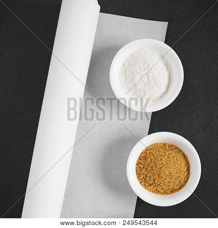 Roll Of White Baking Paper With Flour And Brwn Sugar On The Side, Photographed Overhead On Slate Wit