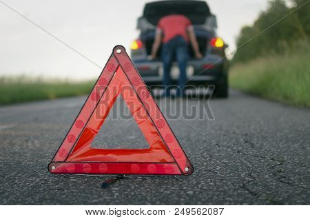 Car Breakdown. Red Emergency Triangle Stop Sign And Driver Near Car Background.