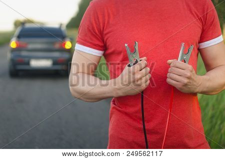 Low Car Battery Charge. Need Recharging. Driver Holding A Automobile Cable Starter In The Hands.