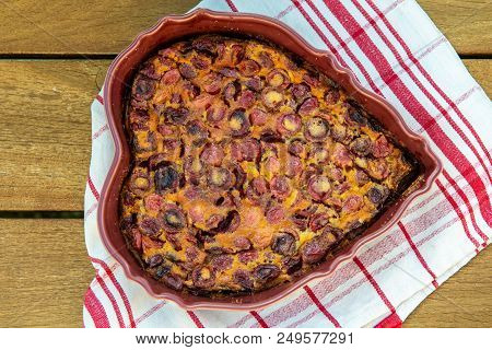A Clafouti With Cherries In The Form Of Heart On A Wooden Table