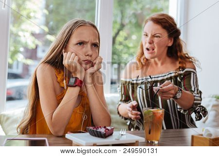 Angry Schoolgirl. Blue-eyed Stylish Schoolgirl Feeling Really Angry While Arguing With Mother