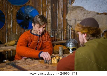 Two Men In Russian Ethnic Suit Playing Medieval Popular Strategy Board Game - Tafl. Folk, Competitio