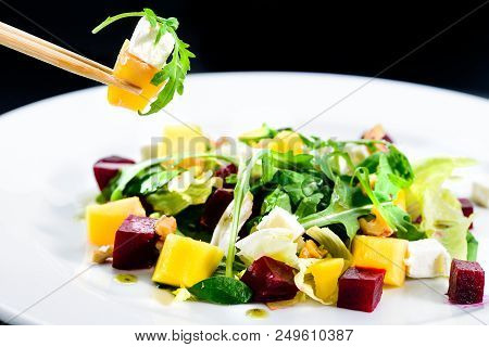 Process Of Eating Delicious And Appetizing Salad With Beetroot And Fruit Mango In A White Plate On B