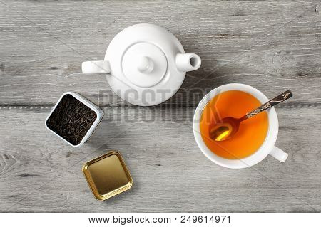 Table Top View - Brass Tea Caddy, White Porcelain Teapot And Ceramic Cup With Silver Spoon And Hot A
