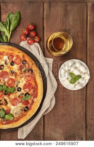 An Overhead Closeup Photo Of A Pepperoni Pizza With A Glass Of White Wine, Basil Leaves, Cherry Toma