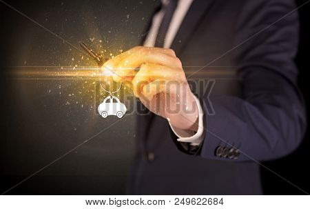 Businessman hand  over shiny keys in dark suit with dark background